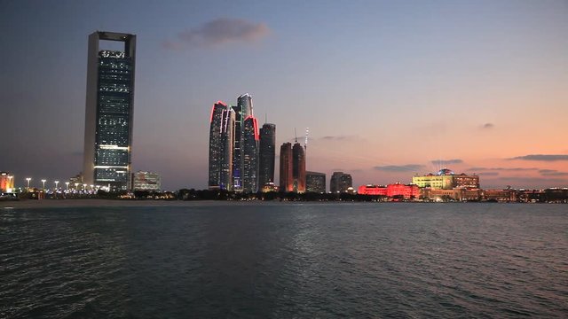 Abu Dhabi skyline at sunset with skyscrapers lit up for the 43rd National day