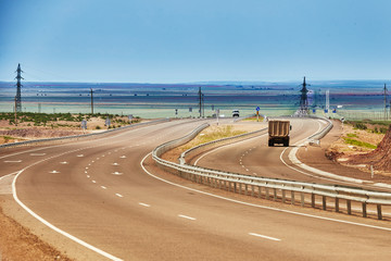 Road in Cental Asia near China boarded. Truck is driving away to horizon.