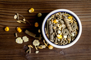 dry food for rodents in bowl wooden background top view