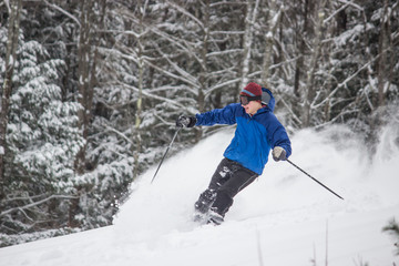 Fototapeta na wymiar Skiing Teen in Blue Jacket Spraying Powder 