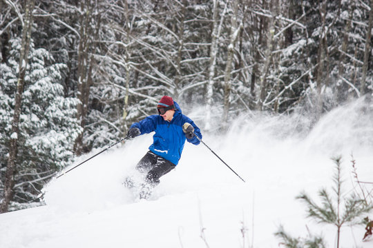Skiing Teen in Blue Jacket Spraying Powder
