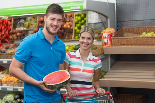 Smiling Couple Buying Dairy Products In Supermarket