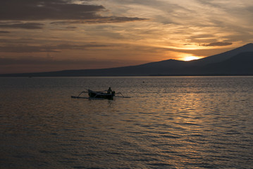 Fototapeta na wymiar Sunset with fisher man fishing in a boat in ocean near Gili Air