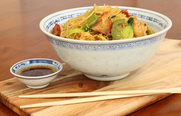 asian noodles with chopsticks and dipping sauce in a blue and white bowl