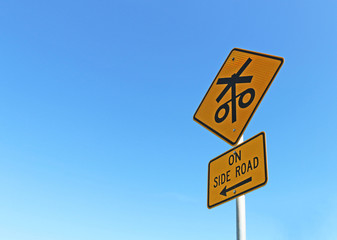 black and yellow trains on side road sign in bright blue cloudless sky
