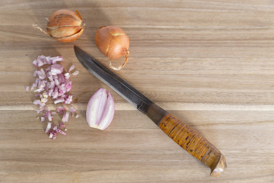 Wooden cutting board with knife and fresh onions