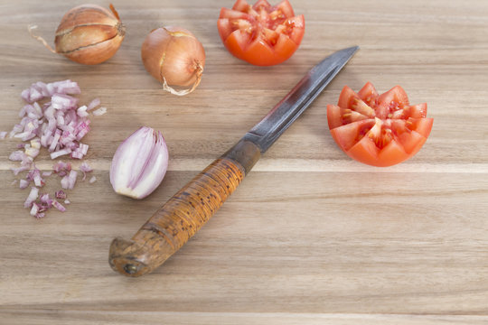 Wooden cutting board with knife, fresh onions and tomatoes