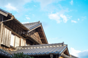 Asia culture concept - japanese traditional historical wooden old house under golden sun and morning blue cloudy sky in Japan
