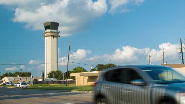 Houston Texas Hobby Airport HOU Air Traffic Control Tower Wide Shot on an Idyllic Afternoon with Sunshine and White Clouds in a Blue Sky with Passing Traffic Driving on the Perimeter Road