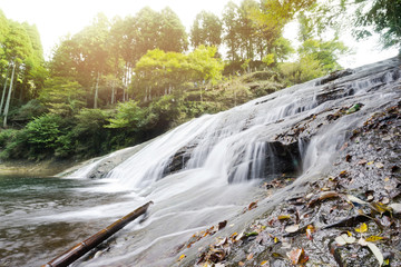 Japan travel concept - beautiful yoro keikoku valley waterfall under dramatic sun glow and morning blue sky in Chiba Prefecture, Japan