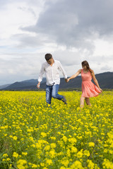 Lovers man and woman walk on the flower field.