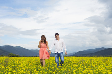 Lovers man and woman walk on the flower field.