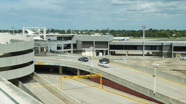 Vehicles Entering Louis Armstrong New Orleans International Airport MSY Driving towards the Terminals and Parking Structures with a Commercial Passenger Airliner in the Background