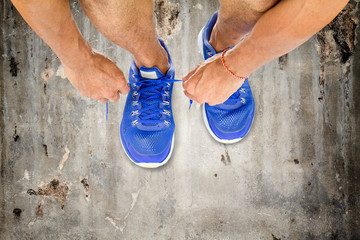 Man lacing sport shoes on old vintage concrete floor, sport exercise concept