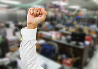 Man arm with white shirt and clenched fist isolated on blurred office background
