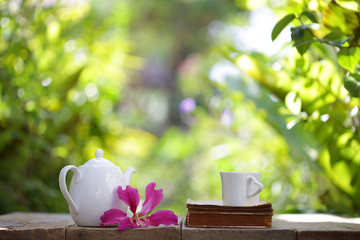 white taa pot and mug with flower and notebook on wooden table
