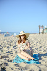 Portrait of a young brunette relaxing on the beach, reading a book