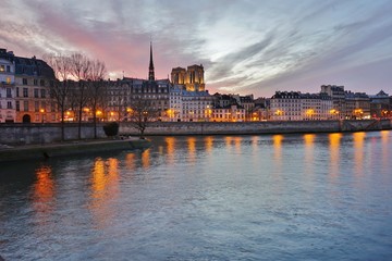 Obraz premium Beautiful pink sky at sunset over the Notre-Dame cathedral and the Seine River in Paris, France