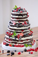 Wedding rustic naked cake with fruits on wooden background
