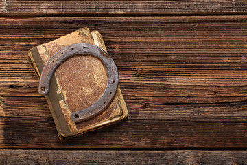 Old book and rusty horseshoe on wooden background