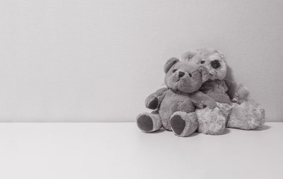 Closeup couple of bear doll on white desk and wall textured background in black and white tone with copy space