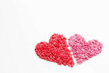 red heart next to the pink heart made of small decorative hearts on white background, focus on the bottom. festive background for Valentine's day, birthday, holiday