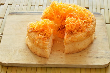 golden egg threads cake cut for piece on wooden chop block