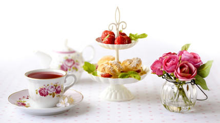 Profiterole or cream puffs cakes filled with whipped cream, strawberries in plateau