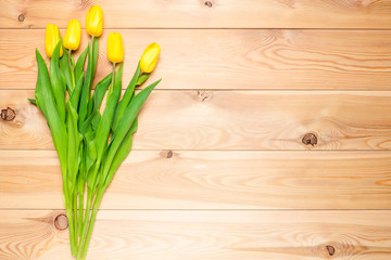 wood background and a bouquet of yellow tulips top view
