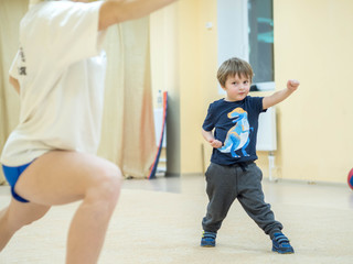 A small child is engaged in physical activity (exercise). Kid makes workout before classes at kung...