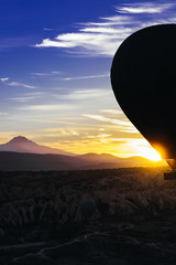 vertical photo of the flight of the balloon over the mountains at dawn in Turkey.