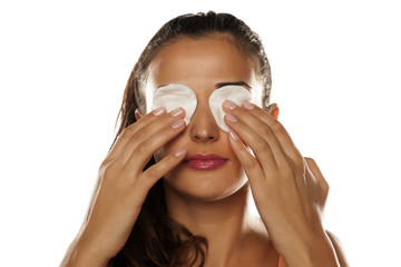 beautiful young woman holding a cotton pads on her eyes © vladimirfloyd
