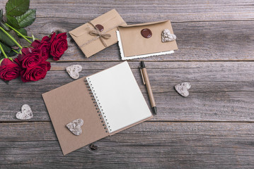 Notebook and roses on a wooden background.