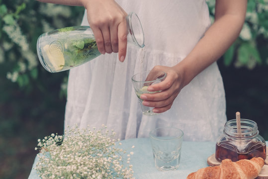 Cropped image of beautiful young girl is pouring lemonade