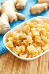 Candied ginger in white bowl on wooden table