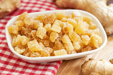 Candied ginger in white bowl on wooden table