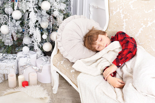 Little Boy Sleeping Under New Year Christmas Tree With Boxes Of Gifts