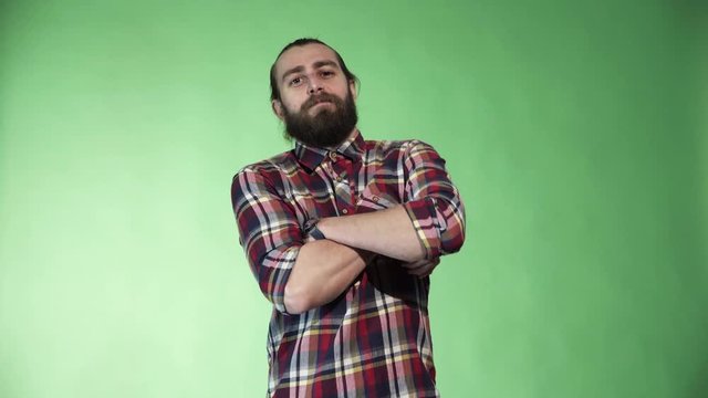 Young satisfied bearded man in plaid shirt posing and gesturing on green chromakey background.
