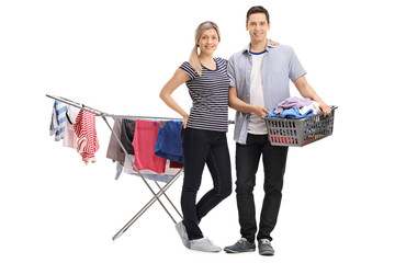 Happy young couple standing in front of a clothing rack dryer
