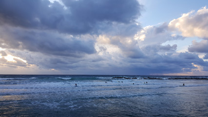 Surfers silhouetted with colourful sky and sea background