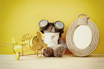 vintage toy plane and cute teddy bear next to empty frame