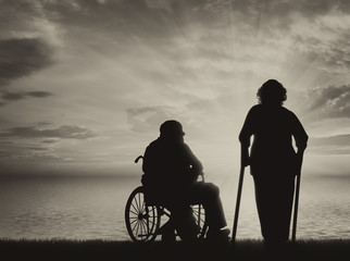 Fototapeta na wymiar Disabled persons near sea in wheelchair and on crutches