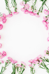 Obraz na płótnie Canvas Wreath frame made of pink wildflowers, green leaves, branches on white background. Flat lay, top view. Valentine's background
