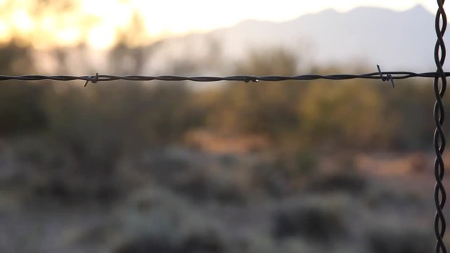 Close up tracking shot of a barbed wire fence on a ranch