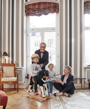 Grandparents and grandchildren with rocking horse and gift