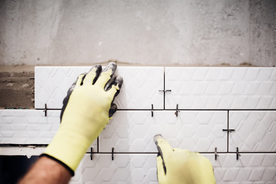 Professional Industrial Worker Installing Small Ceramic Tiles In Bathroom During Renovation Works