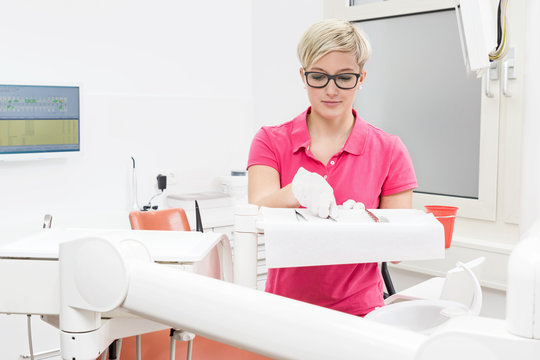 Junge blonde Zahnarzthelferin bereitet Instrumente für Behandlu