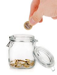 Hand putting one euro coin into money jar isolated on white