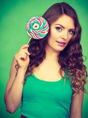 Smiling girl with lollipop candy on green