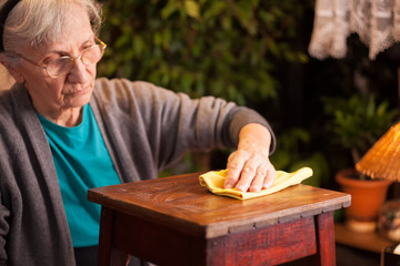 elderly woman dusting furniture